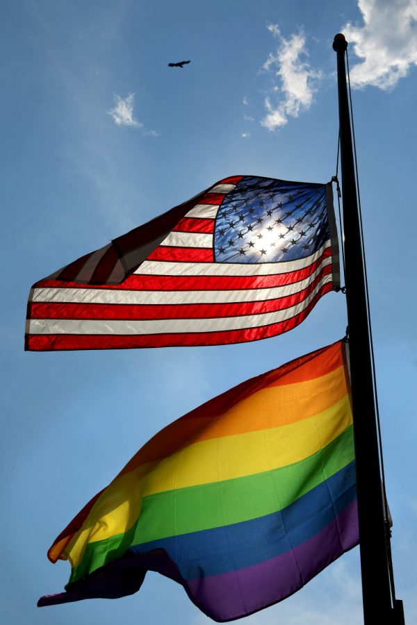 A pride flag flies alongside an American flag.