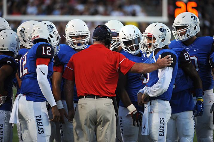 Mitchell+Jonke+and+Grant+Tisdale+lean+into+huddle+led+by+Offensive+Coordinator+Derek+Alford.+