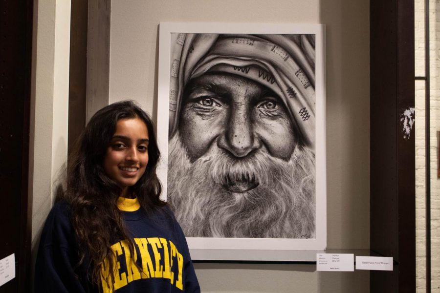 Nikki Shah poses with her charcoal piece, “Old Man.” “I wanted to do a piece that connected to my heritage,” said Shah. Her piece ended up winning third place and stands out with its careful detail. 