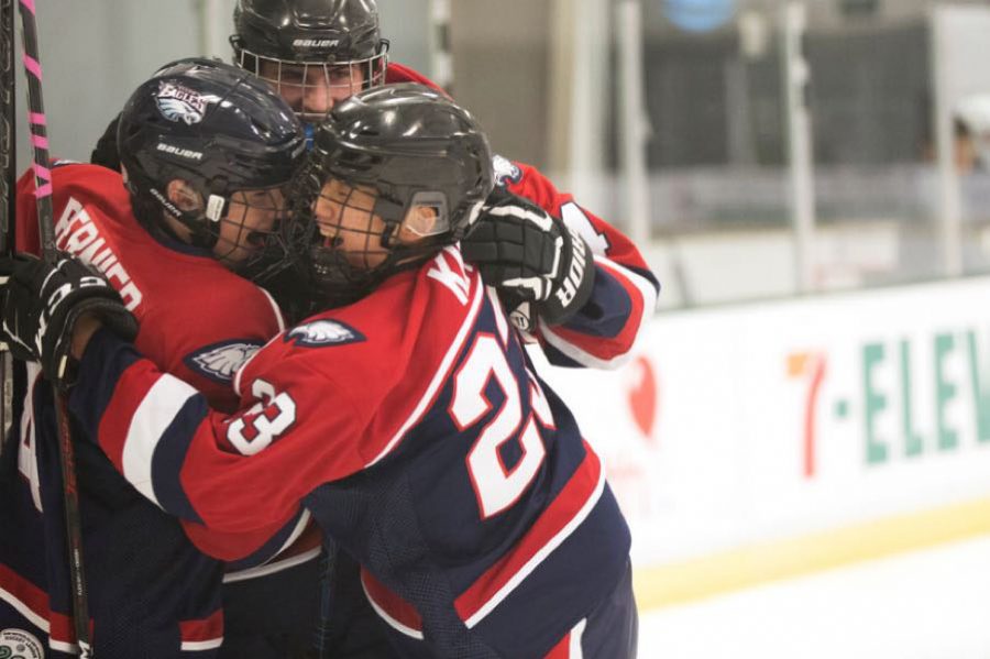 Teammates #4 Robert Bernier, #23 Simon Minsang Kim, and #34 Patrick Mccracken celebrate after a goal is scored.